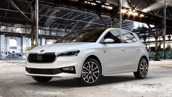Biała Skoda Fabia Monte Carlo z czarnym dachem i felgami stoi w opuszczonej hali przemysłowej z graffiti.