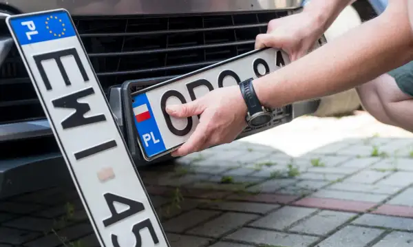 Ręce montują polskie tablice rejestracyjne. Nowa npi rejestracja gotowa do drogi.