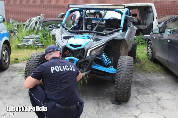 Policjant w mundurze bada quada z niebieskimi elementami.