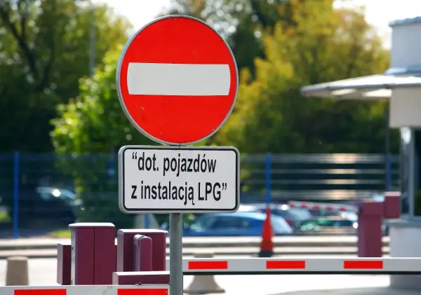 Znak zakazu wjazdu dla pojazdów z instalacją LPG. Barierka wjazdowa i szlaban.
