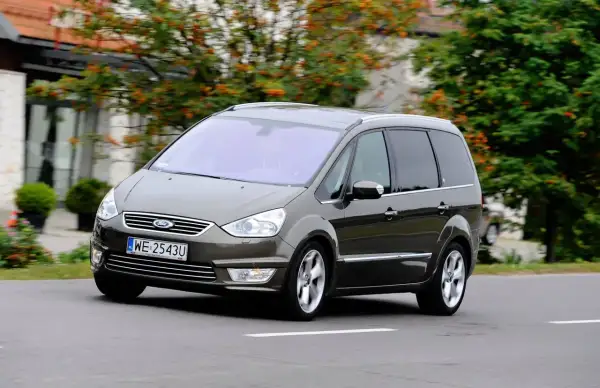 Brązowy Ford Galaxy MK2 w ruchu, z widocznymi felgami i tablicą rejestracyjną WE 2543U.