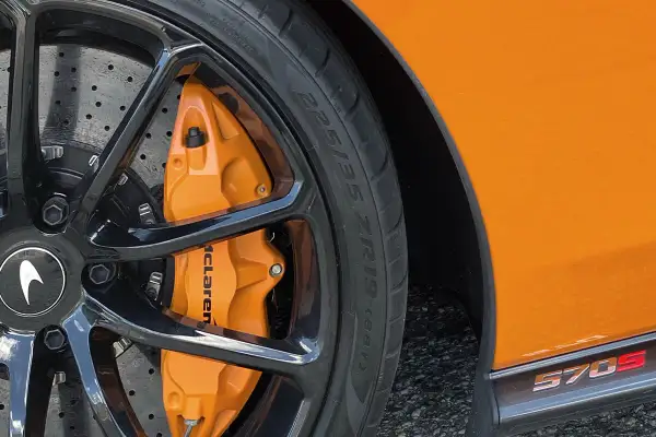 Pomarańczowy zacisk hamulcowy McLaren z oznaczeniami opon 225/35 ZR19 na czarnej feldze.